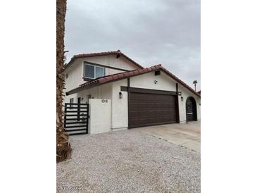 Two story home featuring a terra cotta roof, dark brown garage door and trim, and desert landscaping at 4054 Venita Ct, Las Vegas, NV 89120