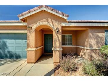 Inviting front entrance featuring an arched entryway, low maintenance landscaping, and a two-car garage at 5292 Cholla Cactus Ave, Las Vegas, NV 89141