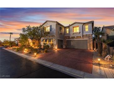 Charming two-story home with a brick driveway, stone accents, and a well-maintained front yard at sunset at 872 Timber Walk Dr, Henderson, NV 89052