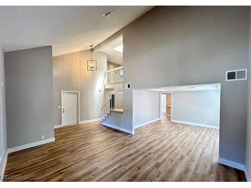 Bright living room featuring wood floors, high ceilings, and stairs leading to a second level at 2428 Greens Ave, Henderson, NV 89014