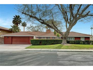Charming single-story home with a well-manicured lawn and mature landscaping and a red tone at 1801 S 15Th St, Las Vegas, NV 89104