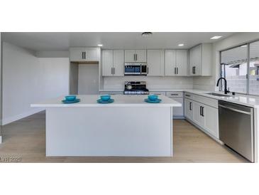 Modern kitchen features white cabinets, stainless steel appliances, island with quartz countertop and stylish finishes at 2205 Mccoig Ave, Las Vegas, NV 89119