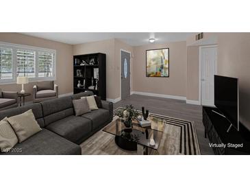 Bright living room with large windows, modern grey L-shaped couch, and stylish decor at 401 Altamira Rd, Las Vegas, NV 89145