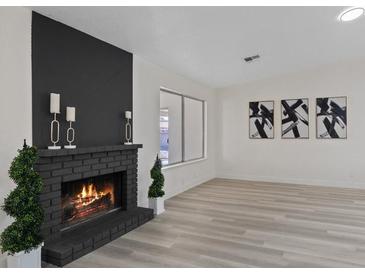 Bright living room boasts a brick fireplace, black accent wall, and decorative artwork at 7138 Sixshooter Dr, Las Vegas, NV 89119