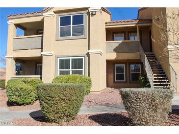 Tan condo building with stairs leading to the second floor and well-maintained landscaping at 2300 E Silverado Ranch Blvd # 1180, Las Vegas, NV 89183