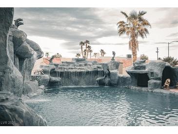 Resort-style pool with rock waterfalls, grotto, and lush landscaping create a private backyard oasis at 4745 Gunlock Cir, North Las Vegas, NV 89031