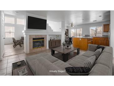Bright living room featuring a fireplace, neutral decor, and open floor plan leading into the kitchen at 6276 Back Woods Rd, Las Vegas, NV 89142