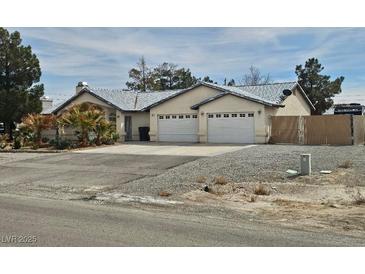 Wide view of property showcasing a multi-car garage, desert landscaping, and ample parking at 901 E Jaybird St, Pahrump, NV 89048