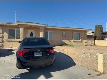 Single-story stucco home featuring a front yard with a desert landscape and a driveway at 1001 Fay Blvd, Las Vegas, NV 89108