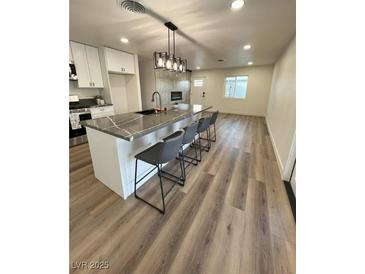 Modern kitchen boasts white cabinets, stainless appliances, granite counters, and stylish island seating at 2413 Valparaiso St, Las Vegas, NV 89108