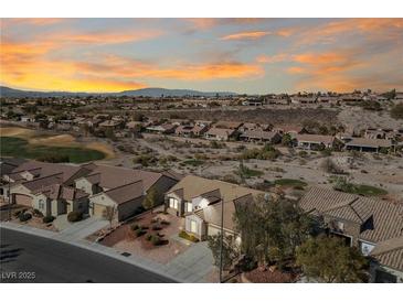 Sunset aerial view of a desert community with mature landscaping and a view of the mountains at 2920 Foxtail Creek Ave, Henderson, NV 89052