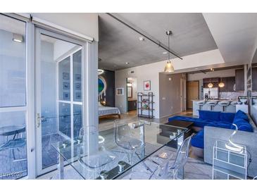 Modern living room with floor-to-ceiling windows, glass table and chairs, and a luxurious blue sofa at 353 E Bonneville Ave # 905, Las Vegas, NV 89101