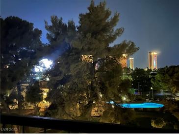 Night view of a community pool with a backdrop of city lights and lush landscaping at 750 S Royal Crest Cir # 346, Las Vegas, NV 89169