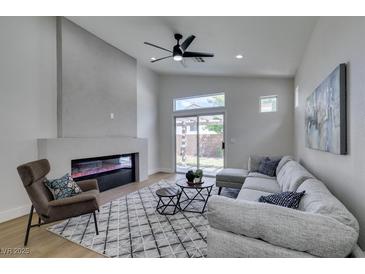 Bright living room features a modern fireplace, ceiling fan, and sliding glass door to the backyard at 10976 Salernes St, Las Vegas, NV 89141