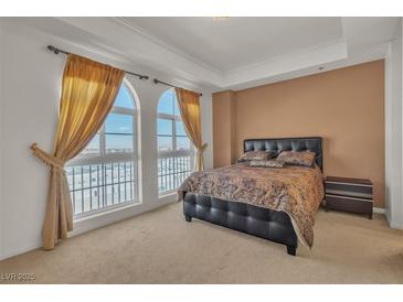 Comfortable bedroom featuring two arched windows with curtains and a decorative tray ceiling at 2405 W Serene Ave # 817, Las Vegas, NV 89123