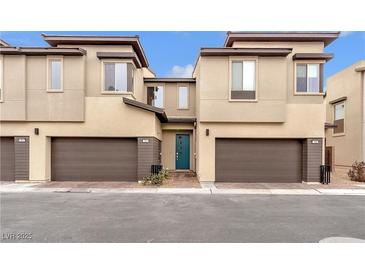 Modern townhome featuring a two-car garage, desert landscaping and a vibrant teal-colored front door at 752 Echelon St, Las Vegas, NV 89138