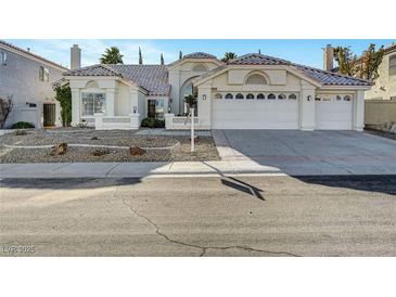 Charming single-story home featuring a three-car garage, desert landscaping, and a classic tile roof at 2221 Loggerhead Rd, Las Vegas, NV 89117