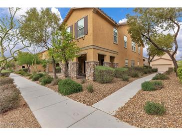Inviting two-story home boasts stone accents, manicured landscaping, and a welcoming front porch with stone columns at 2376 Via Firenze, Henderson, NV 89044