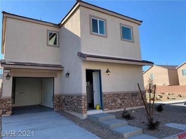 Two-story home with a two-car garage, stone accents, and desert landscaping provides a modern exterior design at 4941 Quest Tribe St, Las Vegas, NV 89122