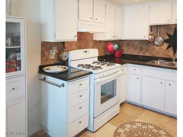 Cozy kitchen with white cabinets, black countertops, and a tile backsplash at 6412 Big Pine Way, Las Vegas, NV 89108