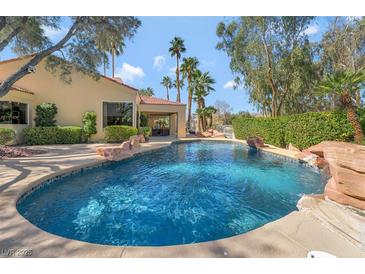 Backyard pool with stone accents and lush landscaping, perfect for relaxing and entertaining guests at 7608 Painted Dunes Dr, Las Vegas, NV 89149