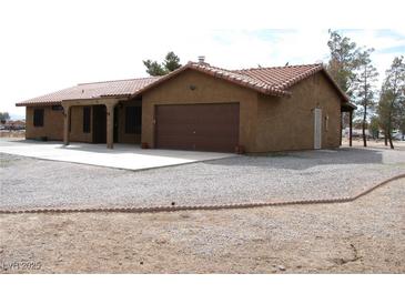 Charming single-story home featuring a tile roof, two-car garage, and desert landscaping at 1081 Pluto St, Pahrump, NV 89048