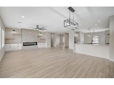 Bright, open-concept living room features a fireplace, custom built-ins, and luxury vinyl plank flooring at 2603 Savannah Springs Ave, Henderson, NV 89052