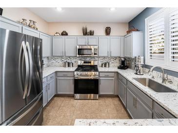 Modern kitchen features stainless steel appliances, gray cabinets, and granite countertops at 10435 Meadow Village St, Las Vegas, NV 89183