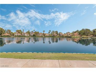 Waterfront homes showcase mature landscaping reflecting in the lake under a bright, partly cloudy sky at 3151 Soaring Gulls Dr # 2113, Las Vegas, NV 89128