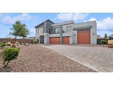 Contemporary gray home featuring a three-car garage, modern architecture, and desert landscaping at 8591 Cloudy Dawn Way, Las Vegas, NV 89113