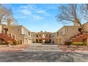 Inviting condo complex with stucco facade, red accents, garages, and well-kept landscaping at 10730 Amber Ridge Dr # 205, Las Vegas, NV 89144