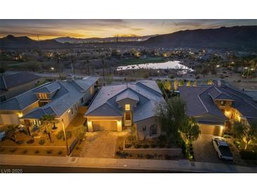 Stunning exterior showcasing a well-manicured lawn, complemented by scenic views of a tranquil lake and majestic mountains at 13 Porto Malaga St, Henderson, NV 89011
