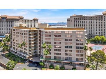 Multi-story condominium building featuring covered parking and a tennis court in the background at 205 E Harmon Ave # 212, Las Vegas, NV 89169