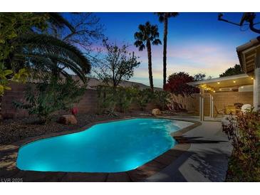 Sparkling pool with lush landscaping and a covered patio in this backyard oasis, perfect for relaxation and entertaining at 4443 Verdiccio Ave, Las Vegas, NV 89141