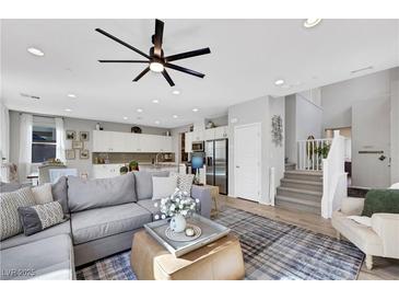 Bright and spacious living room featuring a ceiling fan, modern decor, and seamless access to the kitchen at 632 Loyalty Ct, Henderson, NV 89011