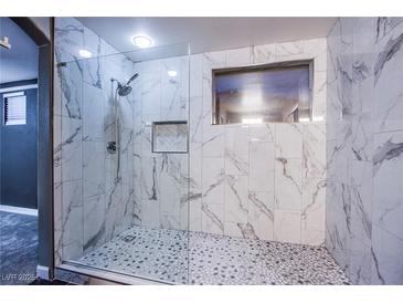 Modern walk-in shower featuring white marble tile surround, pebble flooring and glass enclosure at 913 Evening Fawn Dr, North Las Vegas, NV 89031