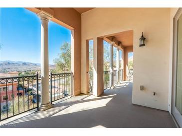 A covered balcony shows an elegant design with pillars and black iron railings providing picturesque community and mountain views at 26 Via Vasari # 204, Henderson, NV 89011