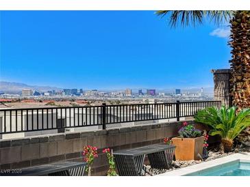 Beautiful Las Vegas city view from patio with black metal railing and landscaping around the pool area at 795 Glistening Light Ct, Henderson, NV 89052