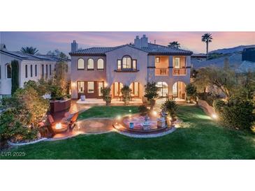An expansive backyard featuring manicured lawn, a fire pit, water feature, and seamless access to the home's elegant living spaces at 11680 Evergreen Creek Ln, Las Vegas, NV 89135