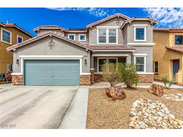 Charming two-story home with a grey exterior, stone accents, a blue-grey garage door, and low-maintenance desert landscaping at 140 Rolling Cove Ave, Henderson, NV 89011