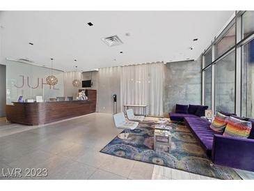 Modern condo lobby with front desk and lounge area with purple sofa and floor to ceiling windows at 353 E Bonneville Ave # 375, Las Vegas, NV 89101