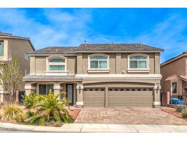 Two-story home with a beige facade, a two-car garage, and a brick driveway at 6484 Mount Eden Ave, Las Vegas, NV 89139