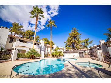 Community pool and hot tub surrounded by well-maintained landscaping and palm trees at 6649 W Tropicana Ave # 101, Las Vegas, NV 89103