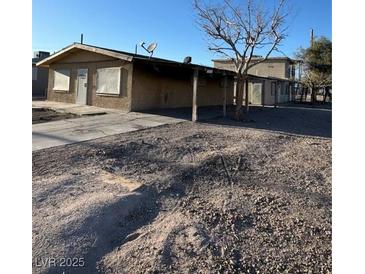 Exterior shot of a one story home with stucco and boarded up windows, plus a covered carport at 709 G St, Las Vegas, NV 89106