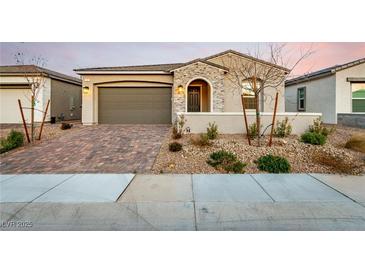 Charming single-story home with a brick driveway, two-car garage, stone accents, and arched entryway at 76 Tatahatso Point St, Henderson, NV 89011
