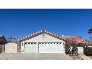 Beige home with a red tile roof and a three car garage with white doors at 8216 Gillette St, Las Vegas, NV 89117