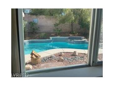 View of a refreshing in-ground pool with rock details and mature landscaping at 1297 Peppercorn Ave, Henderson, NV 89012