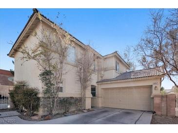 Two-story tan home featuring a two-car garage, desert landscaping, and a tile roof in a residential neighborhood at 1457 Summer Glow Ave, Henderson, NV 89012
