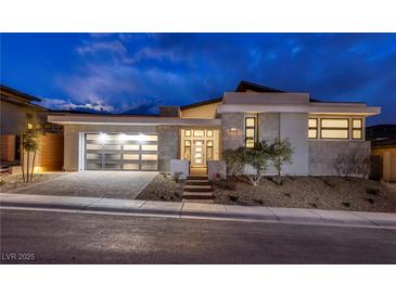 Stunning modern home with a stylish stone facade, a glass garage door, and professionally landscaped yard at 148 Tre Pietre St, Henderson, NV 89011