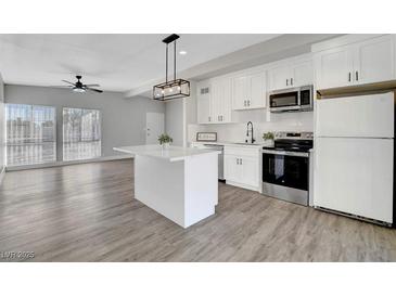 Modern kitchen features stainless appliances, island, sleek countertops, and ample storage space, seamlessly connected to the dining area at 1906 Palora Ave, Las Vegas, NV 89169